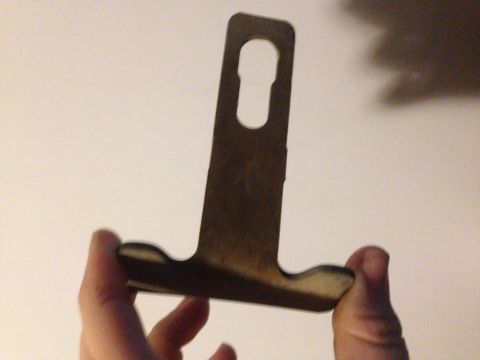 1992 Ford F-150 - A metal bracket, possibly a mounting bracket, is held by two hands against a plain background.