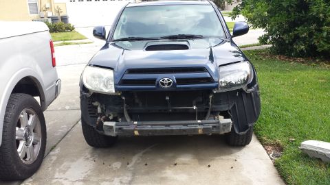 2005 Toyota 4Runner - Front view of a dark blue SUV with its bumper and headlights missing, parked in a driveway.