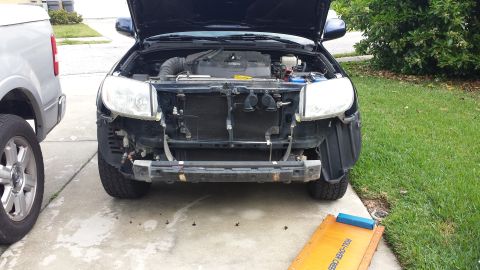 2005 Toyota 4Runner - Front end of a 2005 Toyota 4Runner with bumper removed, undergoing work. Another vehicle is parked nearby.