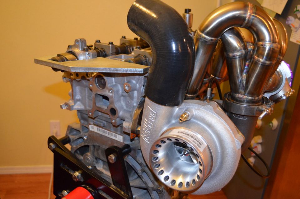 Engine block with turbocharger and exhaust manifold attached. Some text visible on the turbo housing