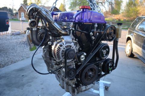 2007 Mazda 6 - Customized engine assembly with a turbocharger and aftermarket purple valve cover is displayed outdoors.