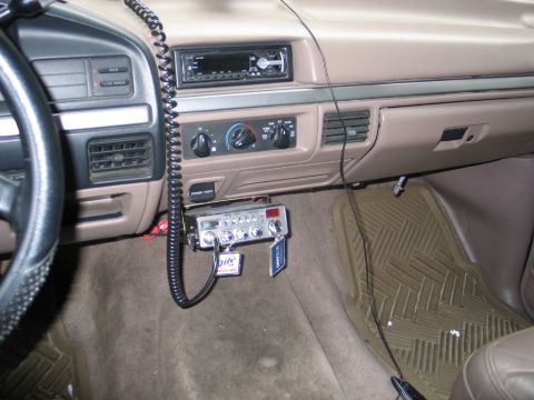 1995 Ford Bronco - The interior of a truck shows a CB radio installed below the dashboard, next to the power outlet.