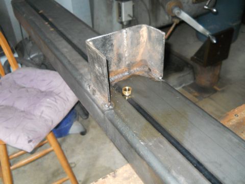 1992 Ford Bronco - A metal frame component with a brass fitting is shown in a workshop setting.
