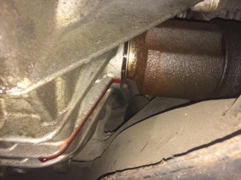 2011 Ford Elite - Undercarriage view of a leaking drivetrain component, with red fluid visible on metal surfaces.