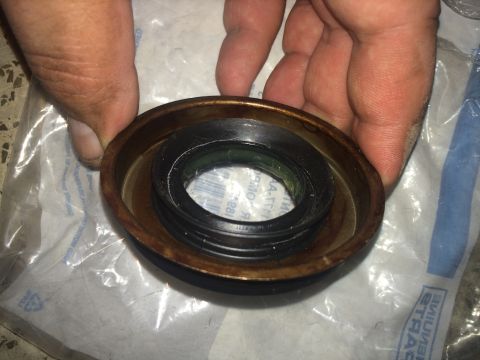 2011 Ford Elite - A person holds an automotive CV shaft seal, showing its internal components and metal casing.