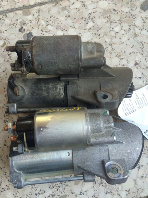 2011 Ford Elite - Two starter motors are shown, one appears to be older and more worn than the other. A label is attached to the newer part.