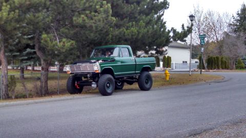 1967 Ford F-250 - A lifted green 1967 Ford F-250 pickup truck is parked on the side of a road in a suburban neighborhood.