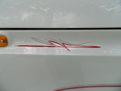 1979 Ford Bronco - A white vehicle displays red and grey pinstripes along its side panel, with a visible orange marker light.