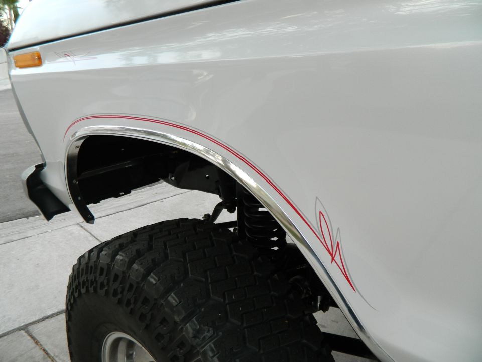White SUV fender with red pinstripes and chrome trim. 1979 Ford Bronco