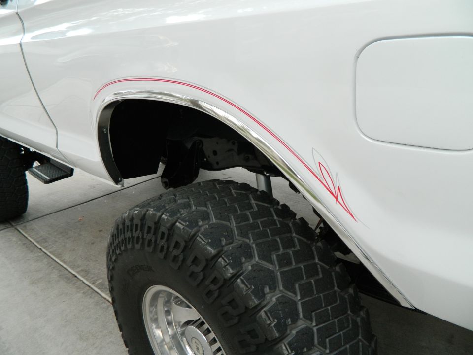 White SUV rear quarter panel with red pinstripes and off-road tire