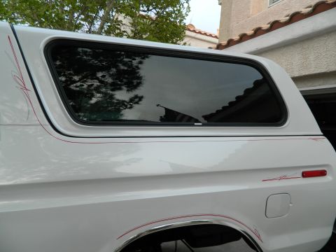 1979 Ford Bronco - White SUV with pinstripes and a camper shell is visible from the side.