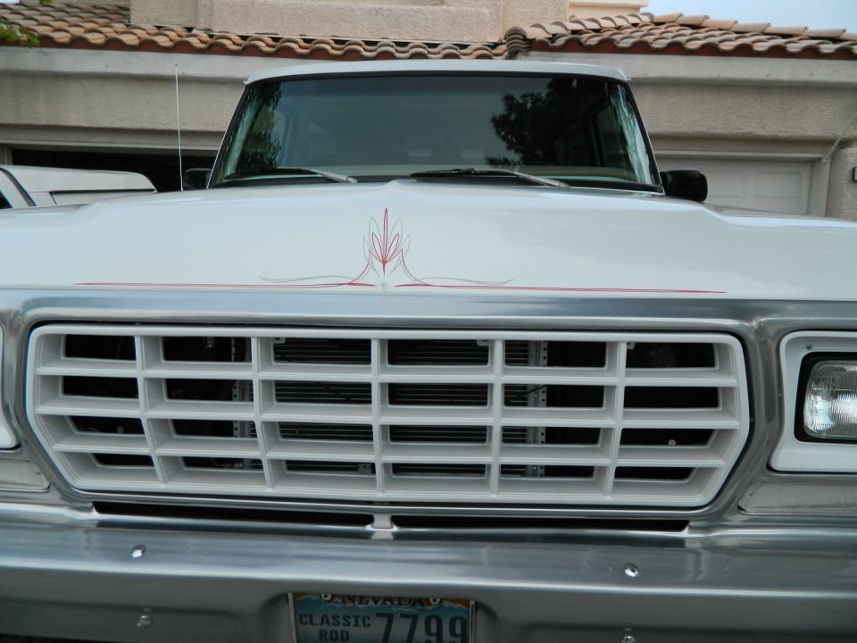 Front view of a white 1979 Ford Bronco with a white grille and red pinstripes on the hood