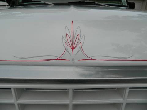 1979 Ford Bronco - White SUV hood displays custom red and grey pinstripe graphics, with a prominent grille visible below.