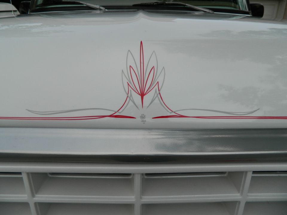 White SUV hood with red and grey pinstripes, close-up on grille and hood ornament area