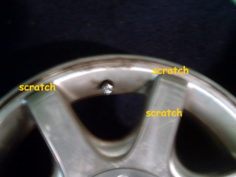 1997 Ford Taurus - Close-up of a scratched silver alloy wheel, showing damage on its rim and spokes.