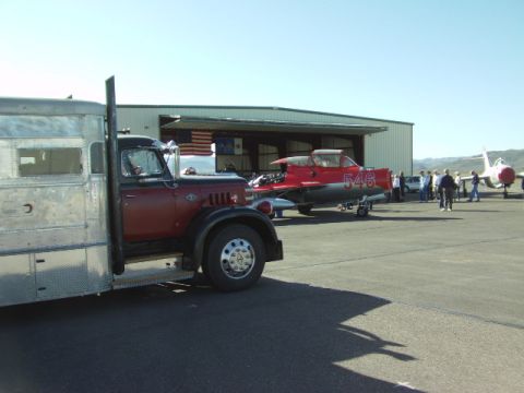 1995 Peterbilt 379 - A vintage truck is parked next to a red jet airplane outside a hangar.