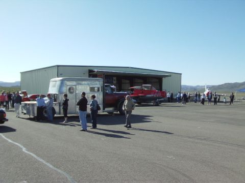 1995 Peterbilt 379 - A truck tows a trailer containing a boat, with several people gathered near a hangar.
