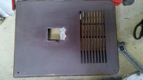 1982 Ford Bronco - A brown door trim panel with a vent and a square cutout is shown, with a wrench nearby.