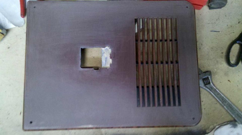 Brown door trim panel with a square cutout and a vertical vent, next to a wrench