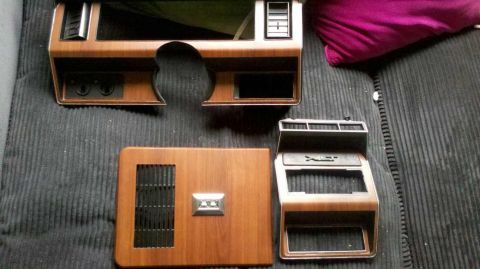 1982 Ford Bronco - Several interior trim pieces, including dashboard sections and a center console surround, are laid out on a dark, textured surface.
