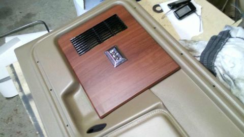 1982 Ford Bronco - Close-up of a vehicle's interior door panel, showing decorative wood grain trim and a speaker grille.