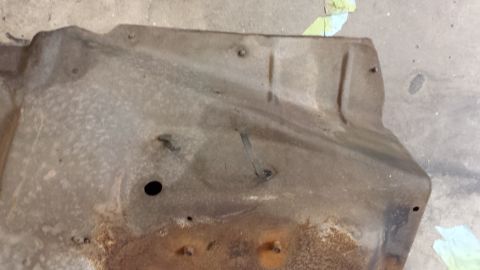 1978 Ford Bronco - This is a close-up of a rusty metal shield, likely from a vehicle's undercarriage.