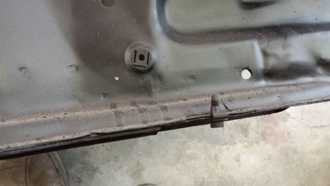1978 Ford Bronco - Close-up view of the underside of a car hood, revealing mounting hardware and a bolt.