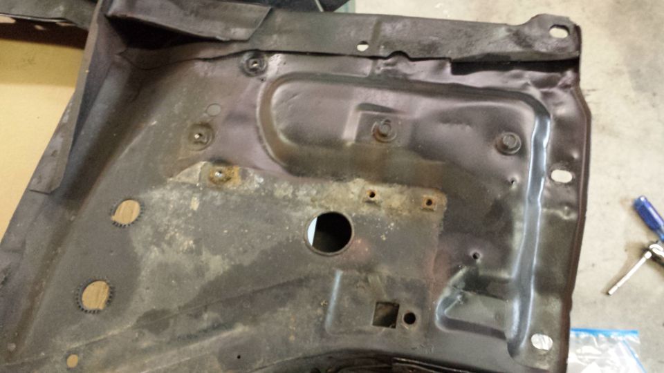 Rusty metal car part with bolt holes and a central circular opening