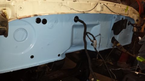 1978 Ford Bronco - The firewall of a vehicle is shown, painted light blue, with a wiring harness connected.
