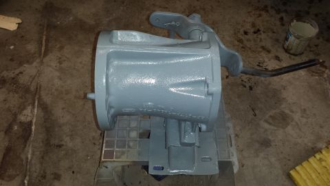 1978 Ford Bronco - A transmission housing, painted gray, rests on a stand in a workshop setting.