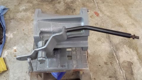 1978 Ford Bronco - A gray metal component with a black lever is shown on a workbench.