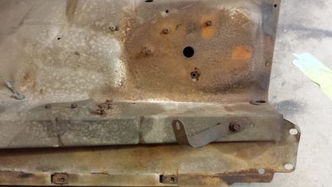 1978 Ford Bronco - This is a close-up view of a heavily rusted metal panel, likely a vehicle part, showing bolts and a mounting bracket.