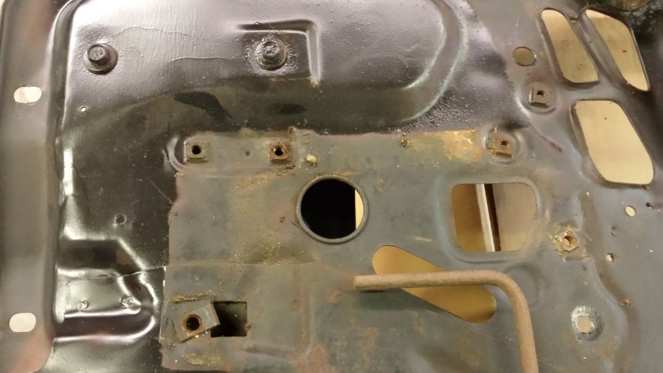 Black metal chassis part with circular hole and rust spots