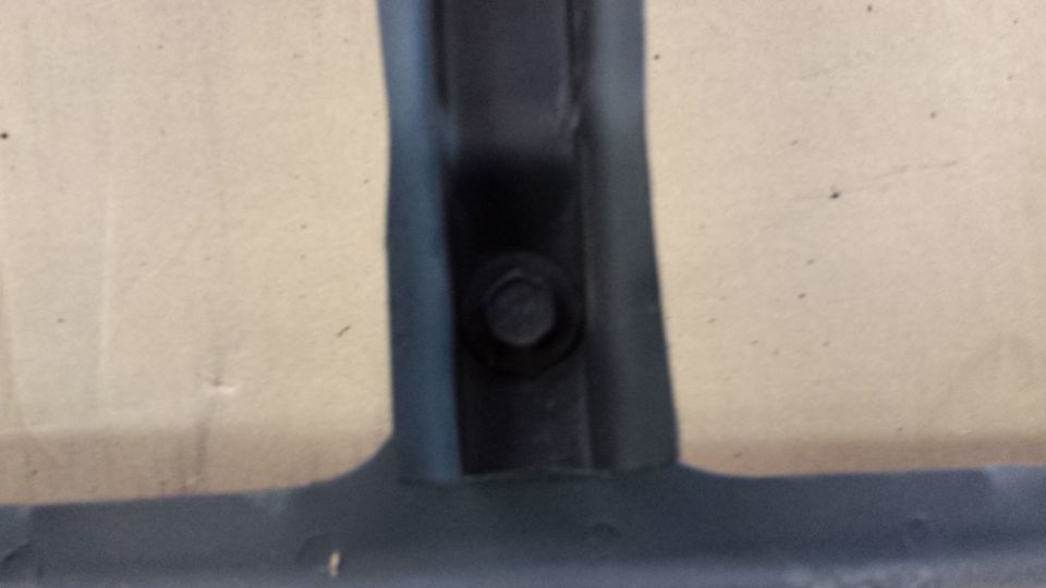 Black plastic trim piece with bolt