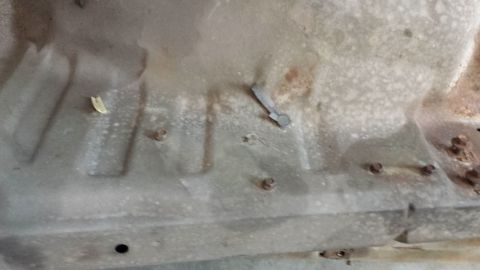 1978 Ford Bronco - Close-up view of the underside of a vehicle, revealing rust and a small metal clip.