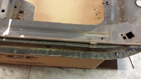 1978 Ford Bronco - Close-up of a rusted metal frame part, possibly from a vehicle, with a box bearing a TCI Automotive logo underneath.