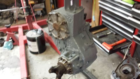 1978 Ford Bronco - A transmission assembly is suspended from an engine hoist in a workshop environment.