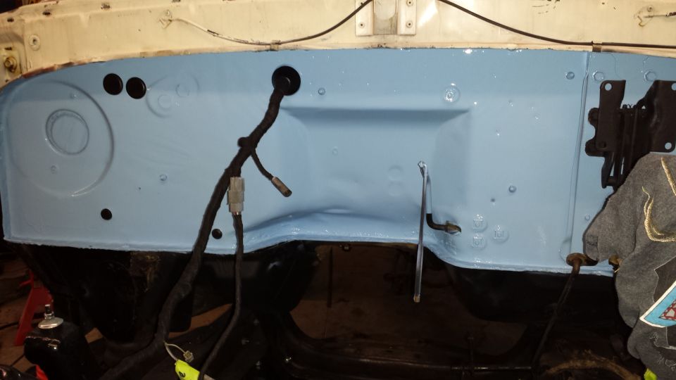 firewall area of a vehicle, painted light blue, with wiring harness