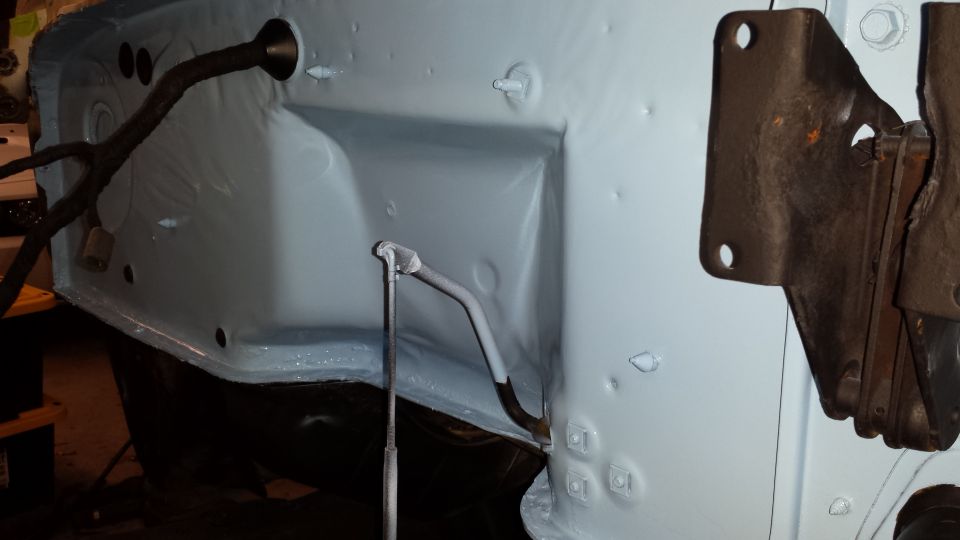 Light blue painted inner fender well with wiring harness and metal bracket