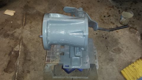 1978 Ford Bronco - Transmission part painted gray, sitting on a stand in a garage.