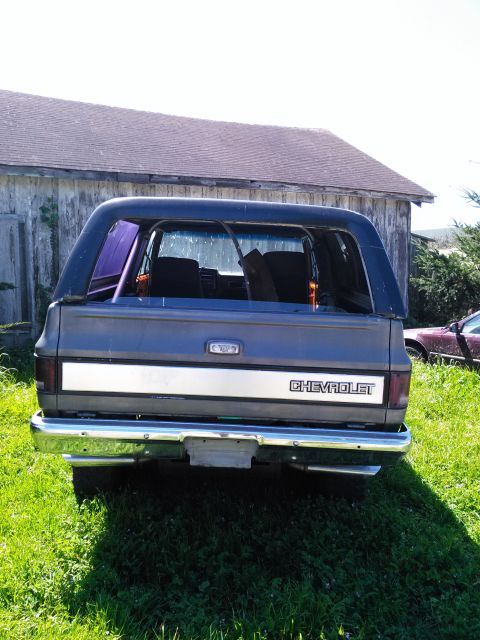 1991 Ford Bronco - The rear of a Chevrolet K5 Blazer is shown parked outdoors with a barn in the background.