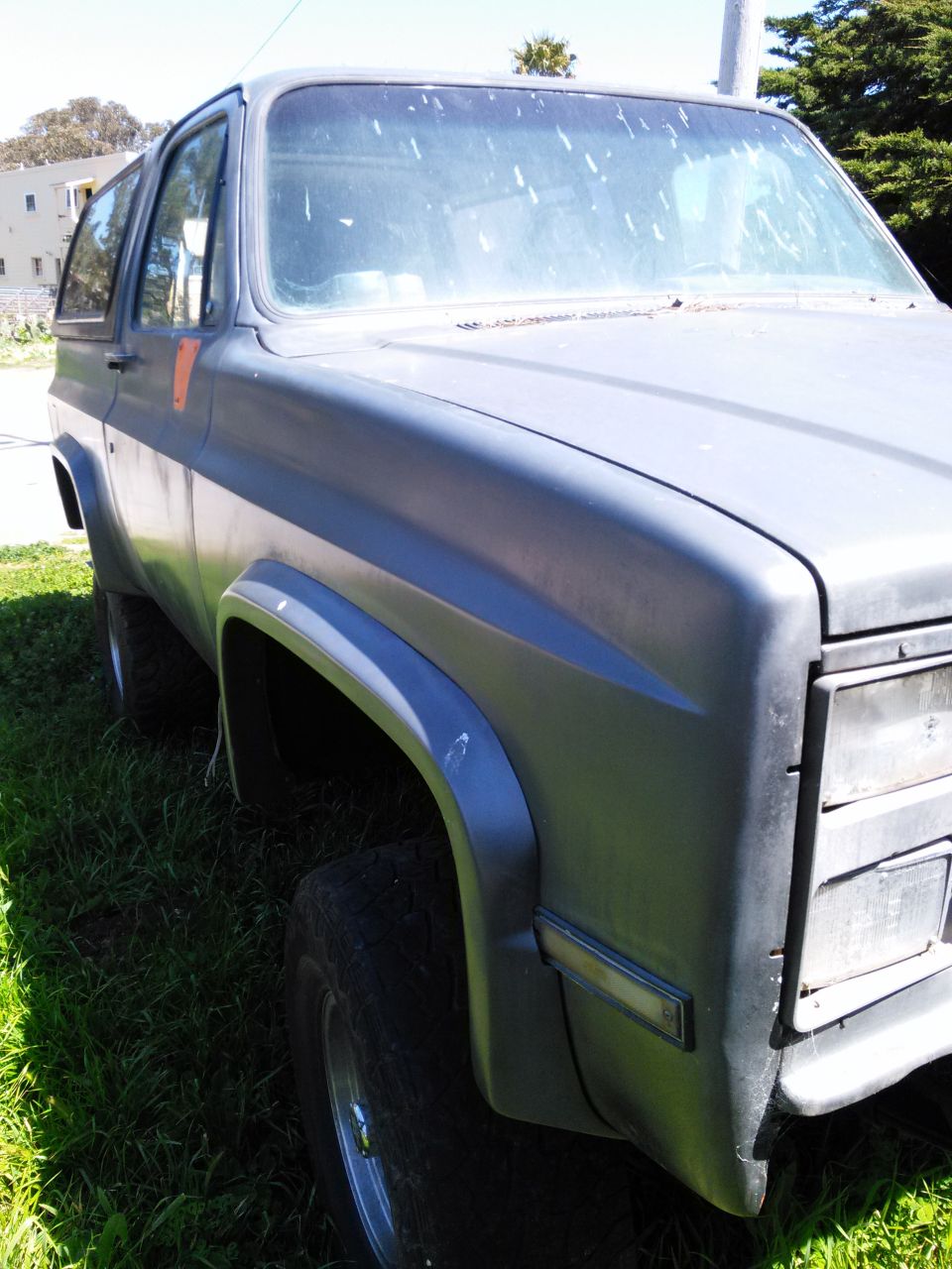 Gray SUV parked on grass, front quarter view. Visible damage on fender