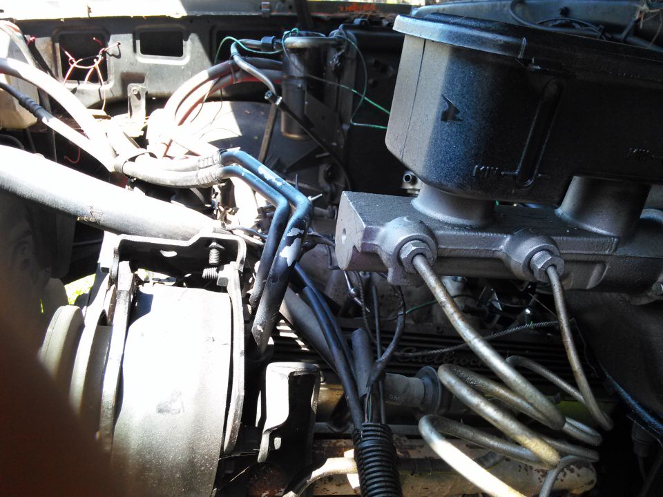 Close-up of a vehicle's engine bay, showing the brake master cylinder and various hoses and wires