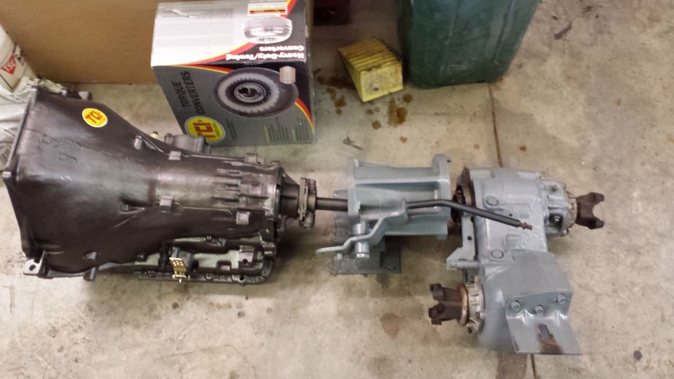 transmission and transfer case assembly on the floor, with a box labeled 'TORQUE CONVERTERS' behind it