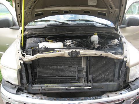 1994 Ford Bronco - The engine bay of a 2004 Dodge Ram 1500 is exposed with the hood raised, revealing the radiator and engine components.