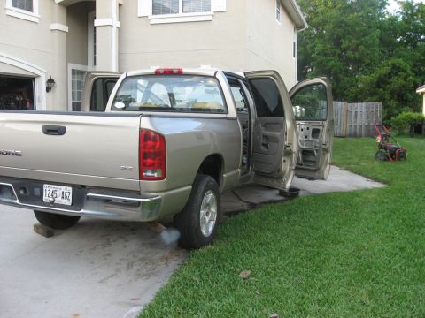 1994 Ford Bronco - Dodge Ram pickup truck parked in a driveway with all doors open, emitting exhaust smoke.