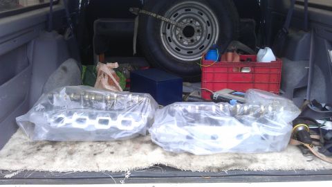 1994 Ford Bronco - Engine parts are stored in the cargo area of a vehicle, alongside a spare tire and various supplies.