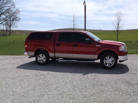 2008 Ford F-150 - This red 2008 Ford F-150 pickup truck is equipped with a camper shell and is shown from the side.
