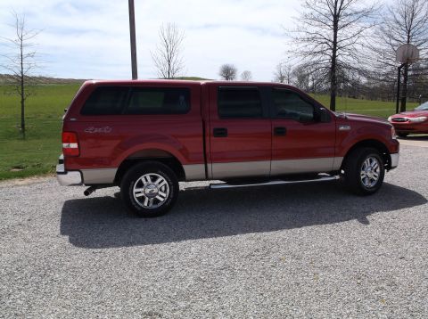 2008 Ford F-150 - Side view of a red pickup truck with a camper shell, parked outdoors. Another vehicle is in the background.