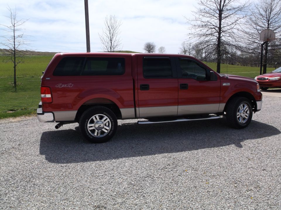 Red Ford F-150 crew cab 4x4 pickup with matching bed cap, passenger side